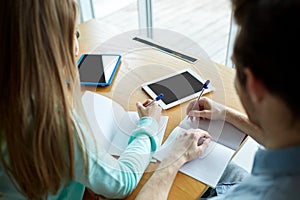 Students with tablet pc writing to notebooks