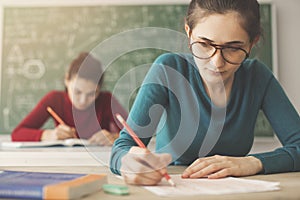 Students taking exam writing answer in classroom