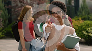 Students talking near university campus outdoors African American happy satisfied student girl woman showing thumb up