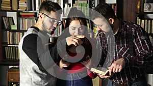 Students talking together in the library and searching for information. Comparing the tablet with the book