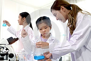 Students and teacher in lab coat have fun together while learn science experiment in laboratory. Young adorable Asian scientist