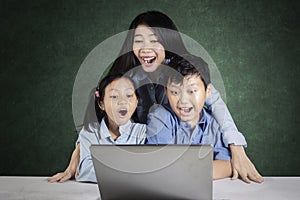 Students and teacher looking at laptop