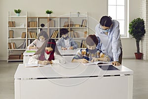 Students and teacher wearing medical face masks in class during Covid-19 pandemic