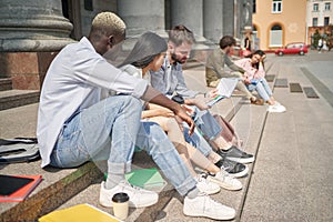 students with textbooks sitting on the steps.