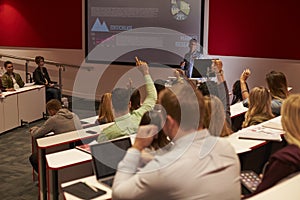 Students at university lecture raise hands to ask questions