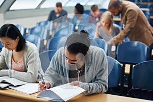 Students, university and writing exam in classroom, information and notes for studying. People, books and knowledge in