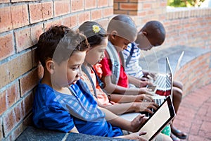 Students using dital tablet and laptop at school corridor photo