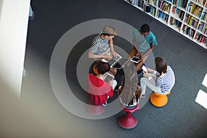 Students using laptop, mobile phone, digital tablet in library