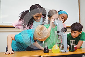 Students using science beakers and a microscope