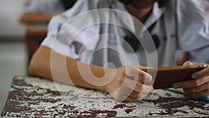Students using smartphone and doing exam answer sheets exercises in classroom of school.16:9 style