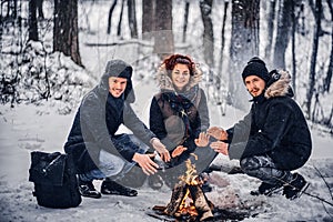 Students warm up at the campfire in the winter forest