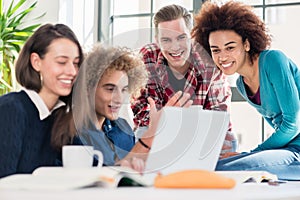 Students watching together a funny online video on a laptop duri