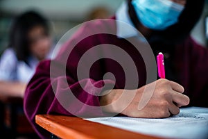 Students wearing mask for protect corona virus or covid-19 and doing exam in classroom with stress