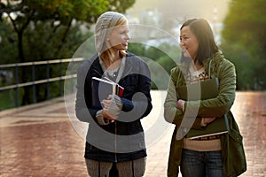 Students, women and friends on campus for university, conversation while walking to class and smile outdoor. College