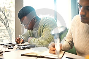 Students, writing or notebooks in school test, university campus exam or college degree notes in classroom library. Men