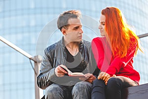 Students a young man and a girl read a book together 