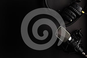 Studio black studio microphone with studio headphones on a black background. Banner. Radio, work with sound, podcasts photo
