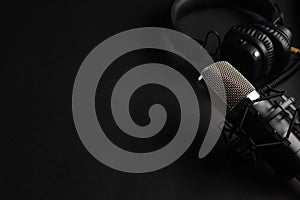 Studio black studio microphone with studio headphones on a black background. Banner. Radio, work with sound, podcasts photo