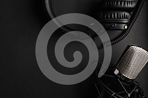 Studio black studio microphone with studio headphones on a black background. Banner. Radio, work with sound, podcasts
