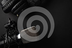 Studio black studio microphone with studio headphones on a black background. Banner. Radio, work with sound, podcasts