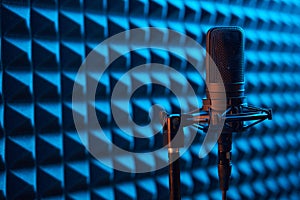 Studio condenser microphone on blue acoustic foam panel background