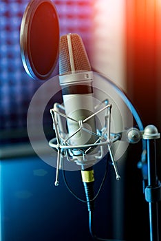 Studio condenser microphone with filter and anti-vibration mount. Live recording with color lights background. Side view