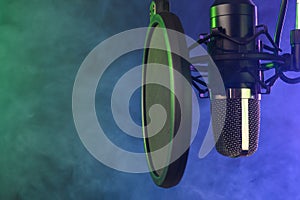 Studio condenser microphone with pop-filter and anti-vibration mount with backlight, color purple and green smoke. Side view with