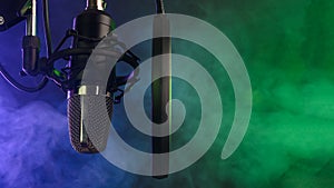 Studio condenser microphone with pop-filter and anti-vibration mount with backlight, color purple and green smoke. Side view with