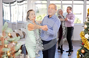 In studio decorated for New Year, elderly man and woman perky dance pair discofox.
