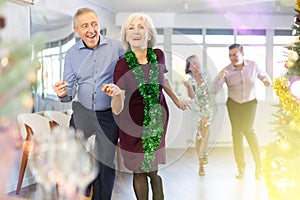 In studio decorated for New Year, elderly man and woman perky dance pair discofox.