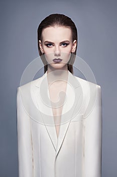 Studio fashion photo of young elegant woman in white men`s jacket