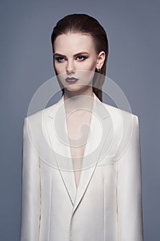 Studio fashion photo of young elegant woman in white men`s jacket