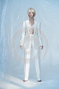 Studio fashion photo of young elegant woman in white men`s jacket