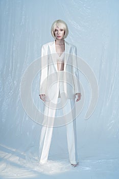 Studio fashion photo of young elegant woman in white men`s jacket