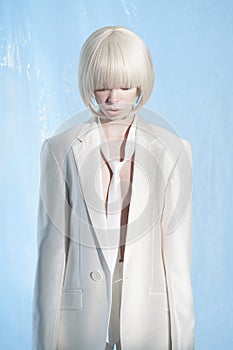 Studio fashion photo of young elegant woman in white men`s jacket