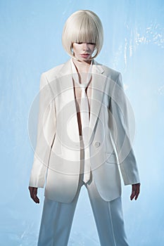 Studio fashion photo of young elegant woman in white men`s jacket