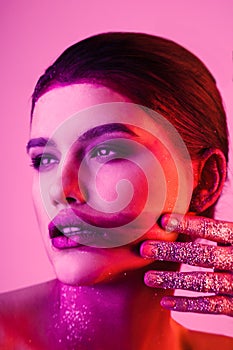 Studio fashion portrait of attractive woman with smeared lipstick and glitter and spangle on hands