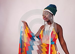 Studio fashion portrait of young African woman in summer dress and ethnic head wrap, white background