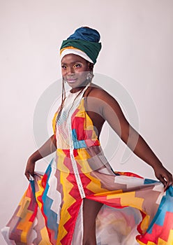 Studio fashion portrait of young African woman in summer dress and ethnic head wrap, white background