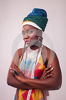 Studio fashion portrait of young African woman in summer dress and ethnic head wrap, white background