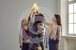 Studio group shot of children standing in circle and holding glowing light bulbs