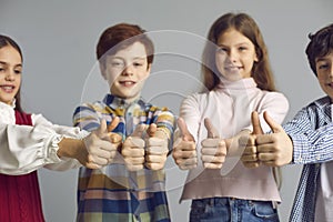 Studio group shot of happy satisfied little children giving thumbs up all together