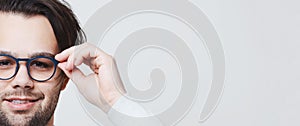 Studio half face portrait of young man wearing eyeglasses on white background with copy space.