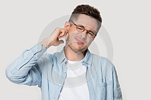 Studio headshot young man suffers from earache or noise