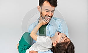 Studio horizontal image of a loving father embraces his cute daughter in his arms. Happy daddy and his little girl playing,