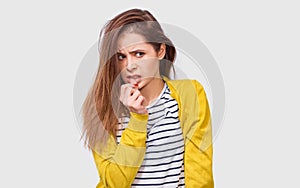 Studio image of doubtful young woman has thinking expression, looking aside to the blank copy space. Student girl can`t make