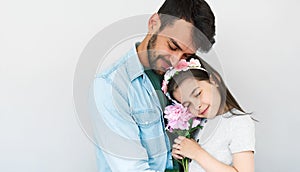 Studio image of handsome father hold embraces his cute daughter and giving her a pink flower. Loving daddy and his little girl