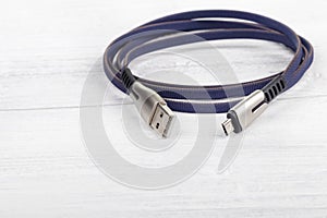 Studio lighting. usb wire for connecting to a computer in blue or purple on a wooden white background in retro style. Close-up