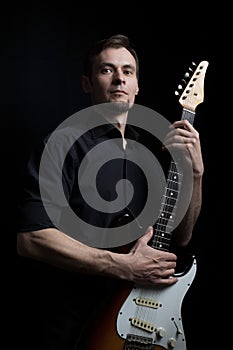 Studio low key portrait of guitarist with electric guitar with classic dark lighting