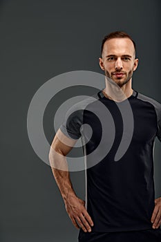 Studio male portrait of handsome powerful athletic man model with healthy muscular body in fashionable black tank top